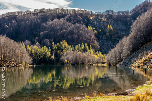 Quiet moment on Lake Santo Modenese with fishermen using their rods and autumn colors, Pievepelago, Italy