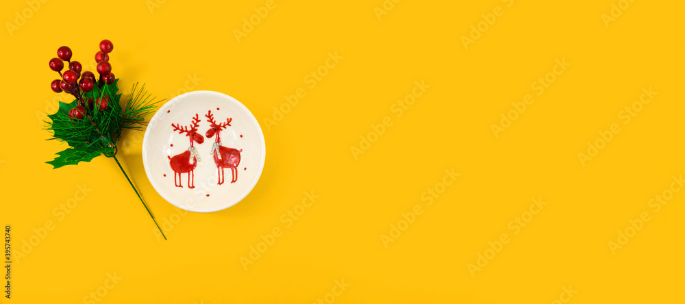 Fototapeta Merry Christmas yellow background, template with a decorative plate pattern of deer and fir branches, banner, copy space