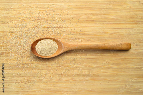 Active granulated yeast, instant dry sourdough, on bamboo cutting board in wooden spoon photo