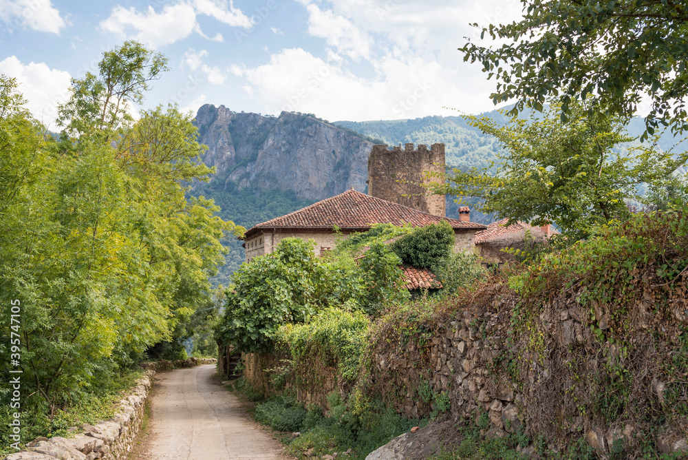 Old stone buildings surrounded by trees and mountains in Mogrovejo, Cantabria, Spain