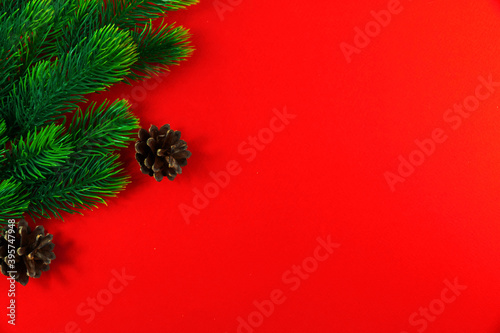 Winter composition  green fir branches and cones  bright red background  copy space  flat lay