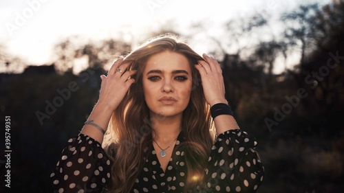 Closeup of a beautiful young woman with a sunset behind her