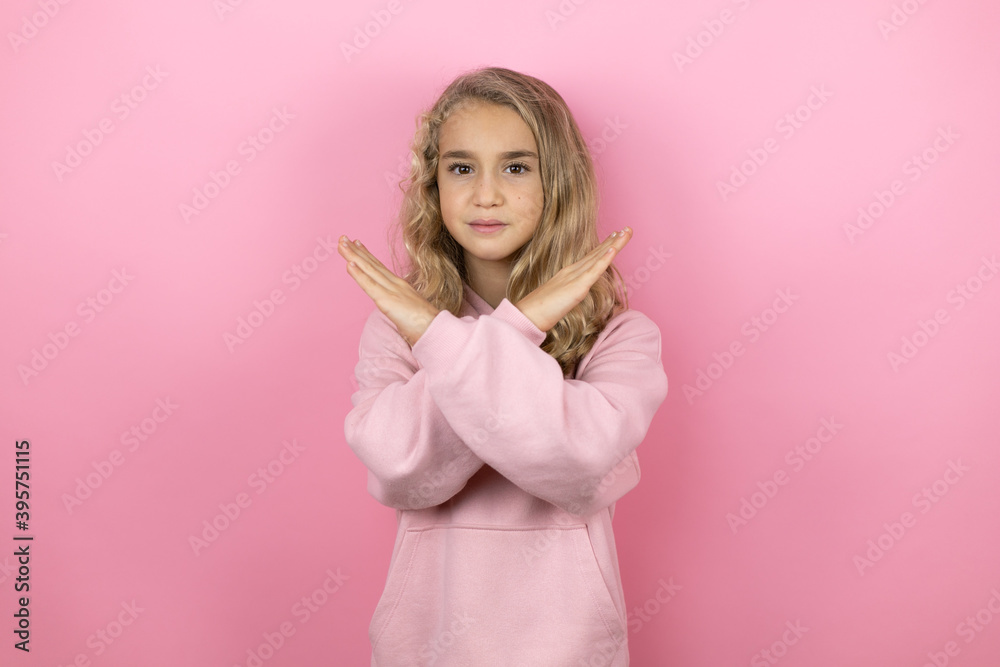 Young beautiful child girl standing over isolated pink background Rejection expression crossing arms doing negative sign, angry face Young beautiful child girl standing over isolated pink background Rejection expression crossing arms doing negative sign, angry face
