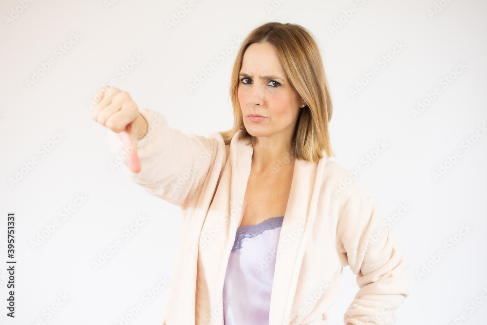 Portrait of beautiful young woman in nightgown pointing down over white background. Portrait of beautiful young woman in nightgown pointing down over white background.
