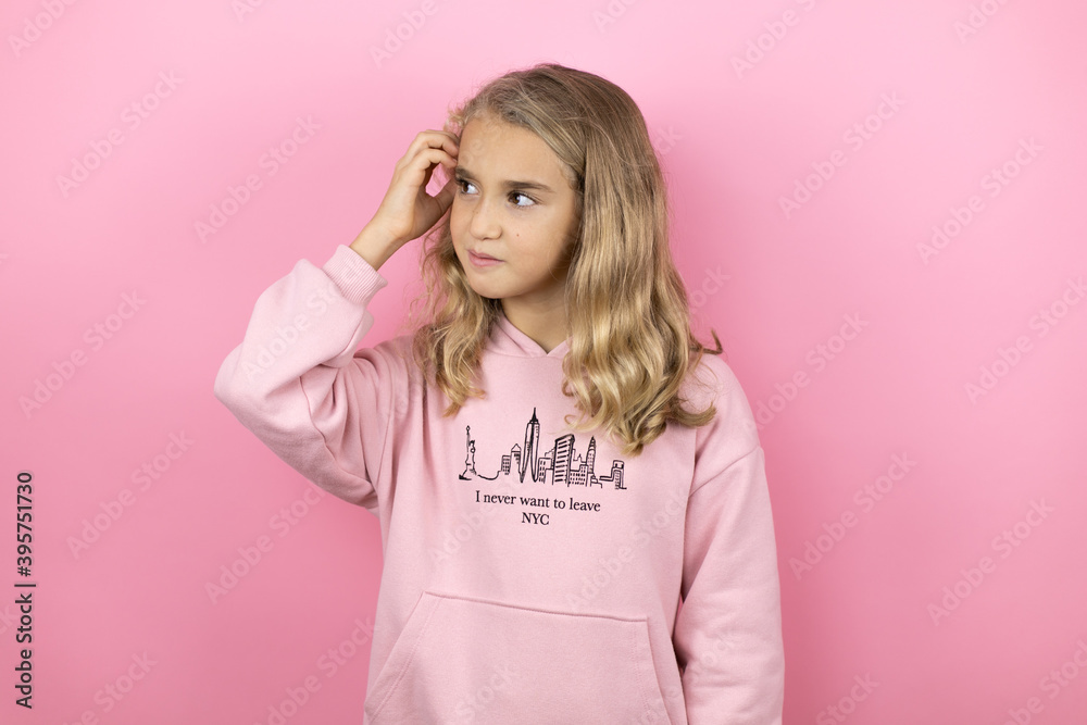 Young beautiful child girl standing over isolated pink background confuse and wonder about question. Uncertain with doubt, thinking with hand on head Young beautiful child girl standing over isolated pink background confuse and wonder about question. Uncertain with doubt, thinking with hand on head