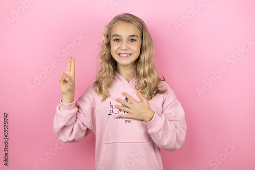 Obraz na płótnie Young beautiful child girl standing over isolated pink background smiling sweari