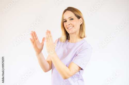 Young pretty woman feeling happy and successful, smiling and clapping hands, saying congratulations with an applause over white background.