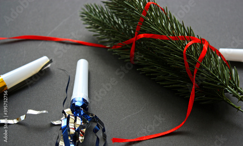 Christmas evergreen ribbon-wrapped branches on a black background. Red ribbon. Festive air whistles. New Year 2021 backdrop. Flat lay.