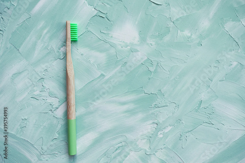 One natural bamboo toothbrush. Plastic free, zero waste concept. Top view, white and greeen background, copy space photo