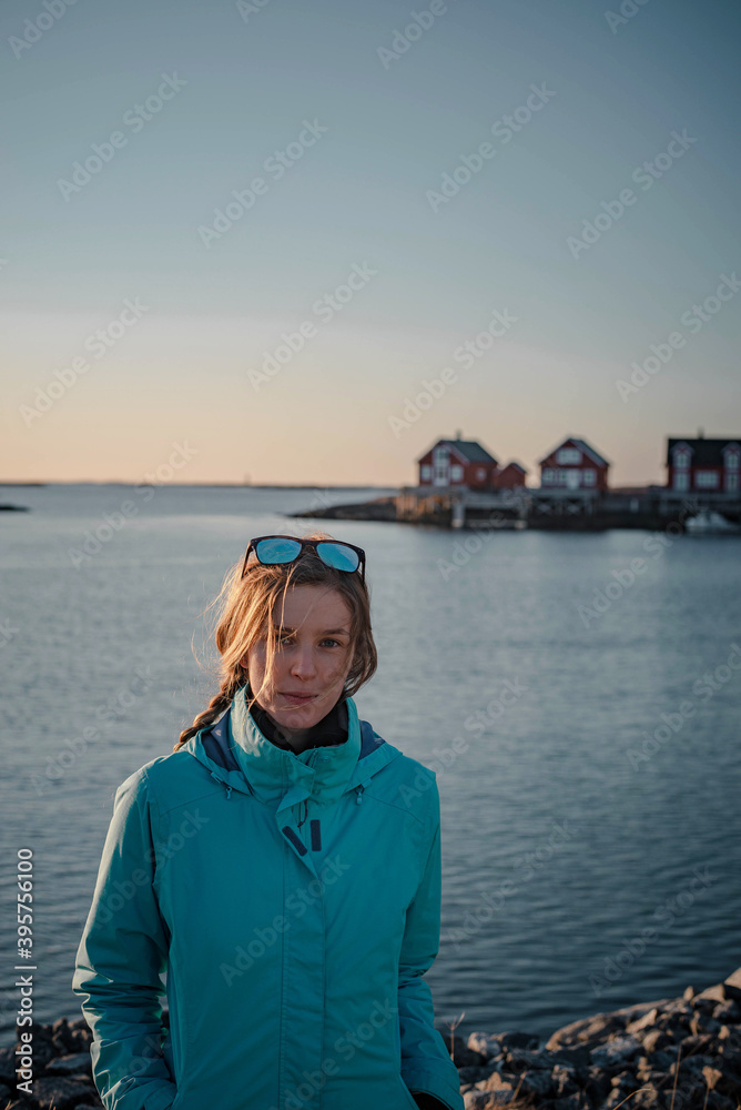 Naturally blonde woman during a hike around Nord Trondelag with typically red houses in background