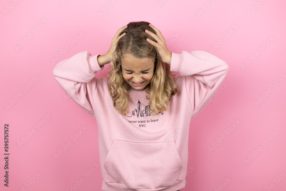 Young beautiful child girl standing over isolated pink background suffering from headache desperate and stressed because pain and migraine with her hands on head Young beautiful child girl standing over isolated pink background suffering from headache desperate and stressed because pain and migraine with her hands on head
