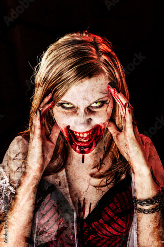 Studio portrait of a female vampire or zombie with open mouth, evil smile looking at camera