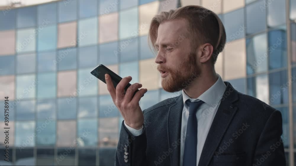 Angry businessman boss Shouts at the smartphone. Handsome bearded man having intense negotiations, while standing on a balcony of business center with morrired windows. Slow Motion 4K Angry businessman boss Shouts at the smartphone. Handsome bearded man having intense negotiations, while standing on a balcony of business center with morrired windows. Slow Motion 4K
