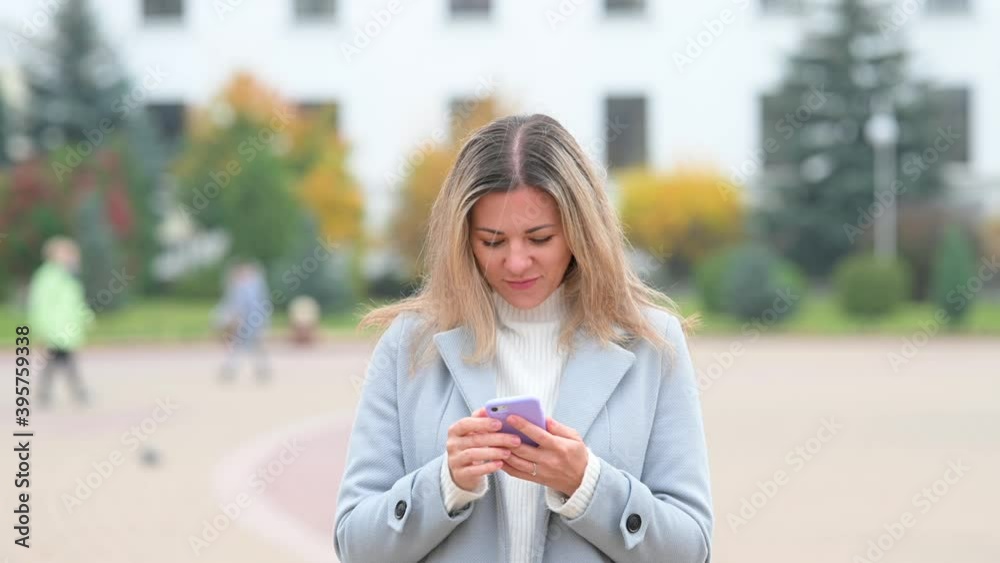 Portrait of happy girl typing by mobile phone on city street. Communication, social networks, shopping concept. Portrait of happy girl typing by mobile phone on city street. Communication, social networks, shopping concept.