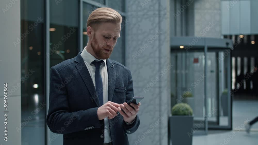 Handsome bearded Startup Businessman using mobile Phone. Young man texting Messages, cheating on his Smartphone while walking in Office District. Business. Social Networking. People. Apps.