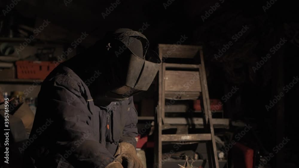 Man picks up electrode holder preparing to begin Shielded metal arc welding stainless steel. MID TILT SHOT Man picks up electrode holder preparing to begin Shielded metal arc welding stainless steel. MID TILT SHOT