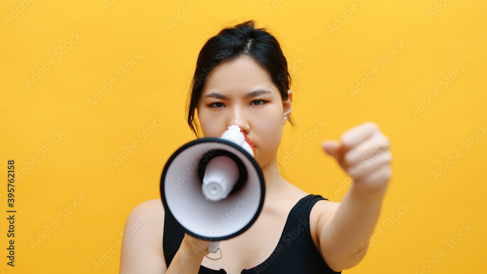 Portrait of angry passionable young asian woman shouting into the loudspeaker. High quality photo Portrait of angry passionable young asian woman shouting into the loudspeaker. High quality photo