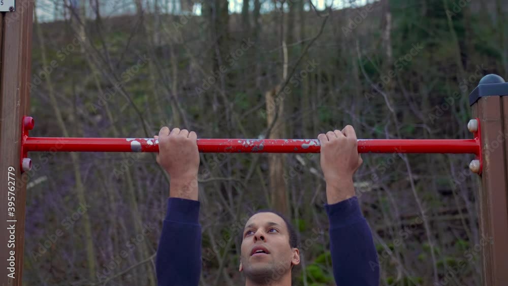 Handsome black adult man exercising and doing pull-ups outside, slowmo Handsome black adult man exercising and doing pull-ups outside, slowmo