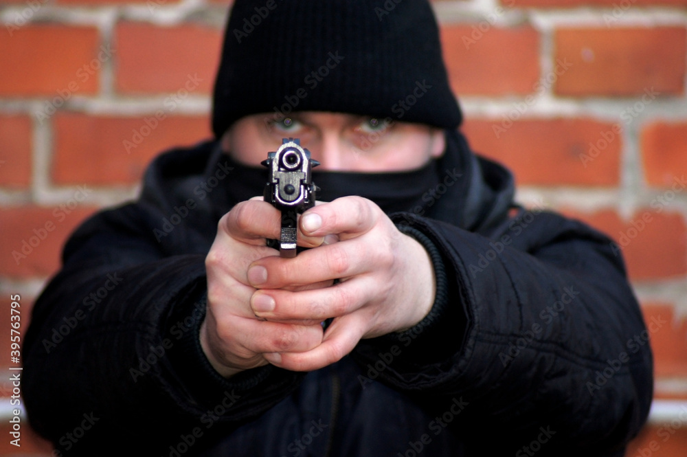 Maskierter Mann mit Schusswaffe in den Händen Maskierter Mann mit Schusswaffe in den Händen