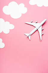 top view of white plane model on pink with clouds