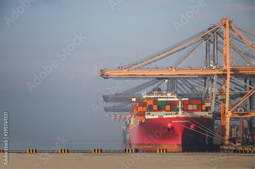 Pink ship container cargo entering commercial port, Logistics and transportation of container cargo pink ship and cargo logistic import export background and transport sunset twilight