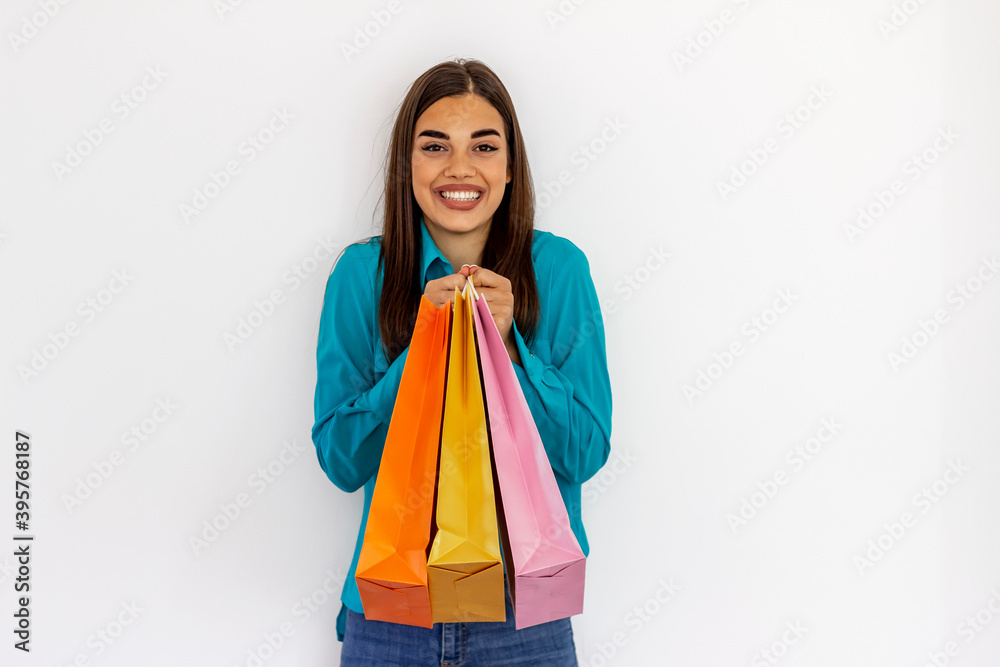 Portrait of a happy smiling young teenage girl in with shopping bags over white background.Attractive young woman in blue shirt with shopping bags over grey background.Sale, outlet and people concept. Portrait of a happy smiling young teenage girl in with shopping bags over white background.Attractive young woman in blue shirt with shopping bags over grey background.Sale, outlet and people concept.