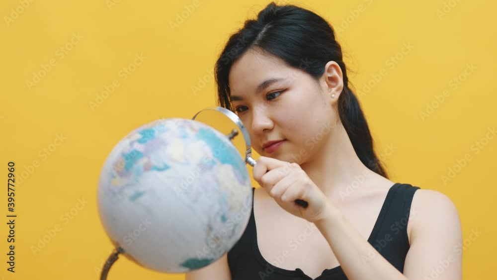 Young asian woman examining the globe with a magnifying glass. High quality 4k footage Young asian woman examining the globe with a magnifying glass. High quality 4k footage