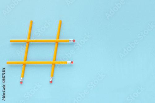 Hashtag sign made from yellow pencils on a blue background with copy space  top view. Wooden yellow pencils on a blue background with copy space. Hashtag is popular on the internet. Minimalism.
