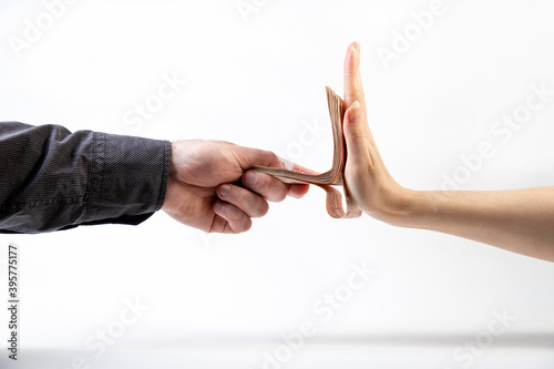 Bild auf Leinwand A man's hand in a black shirt gives a stack of money to a woman's hand, which refuses