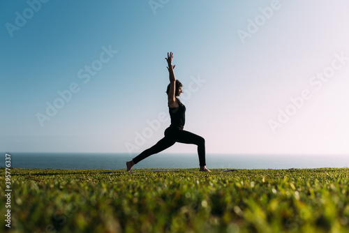 Bild auf Leinwand Mujer adulta delgada estira sus brazos al cielo practicando yoga en la tarde en exteriores