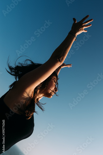 Mujer adulto estira los brazo hacia el cielo despeinada practica yoga.