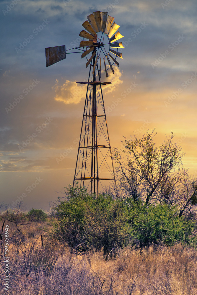Agricultural farm water pump windmill in the field during sunset