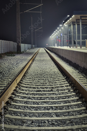 Aufnahme einer leeren Gleisanlage in den Nachtstunden auf einem hell beleuchteten Bahnsteig