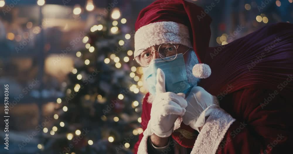 Santa Claus in mask walking past Christmas tree