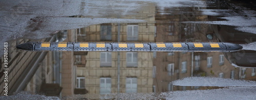 Black and yellow speed bump in a puddle on the pavement photo