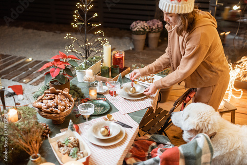 Woman serving and decorating a festive dinner table on the christmas eve outdoors on the terrace
