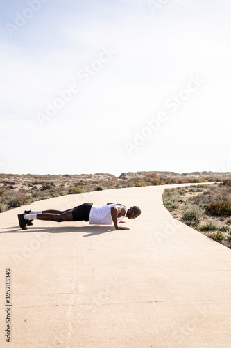 Vertical shot of young black runner in profile doing push-ups.
