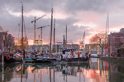 Rotterdam, The Netherlands, November 5, 2020: Bierhaven harbour with historic barges and both harbour and construction cranes under a spectacular sky at sunset
