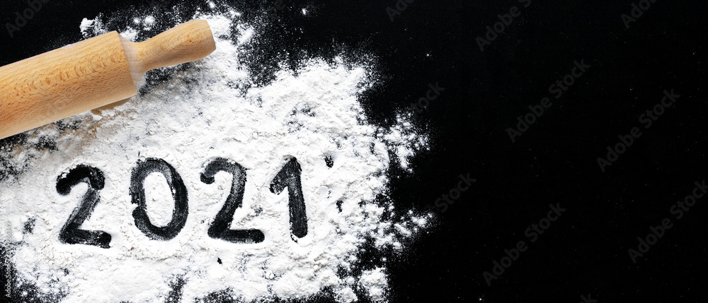Preparation for cooking home made cookie. Baking flour and 2021 on black board. Top view, flat lay with space for text. rolling pin, flour and shape of new year. New year ornament food background - obrazy, fototapety, plakaty 