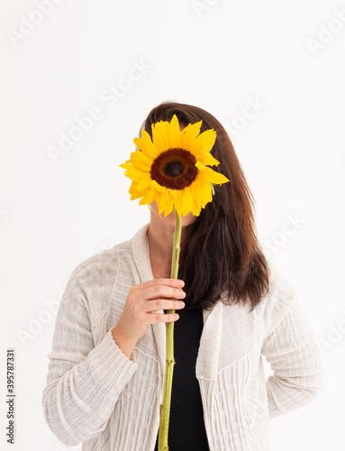 Fototapeta Naklejka Na Ścianę i Meble -  Caucasian woman covering her face with sunflower on white background