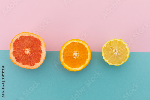 Grapefruit, orange and lemon halves on pink and blue background