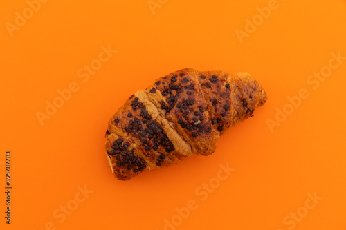 High angle view of chocolate croissant on orange background