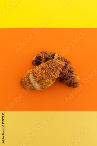 High angle view of two croissants on orange background