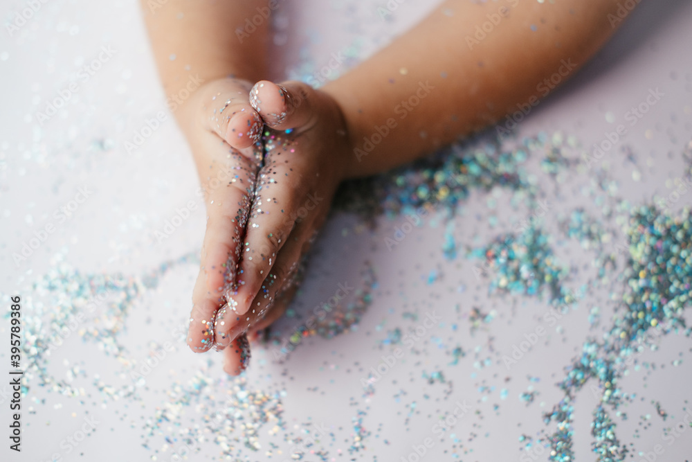 Fototapeta premium small children's hands in glitter sequins . Christmas new year holidays.