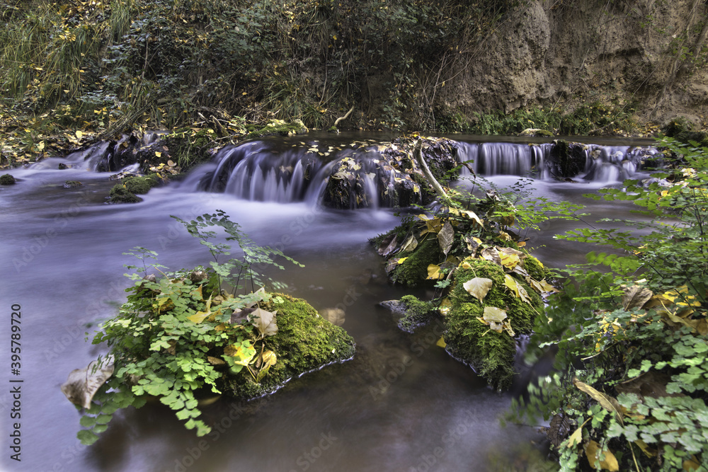 Small water cascade with a silk effect in the autumn forest