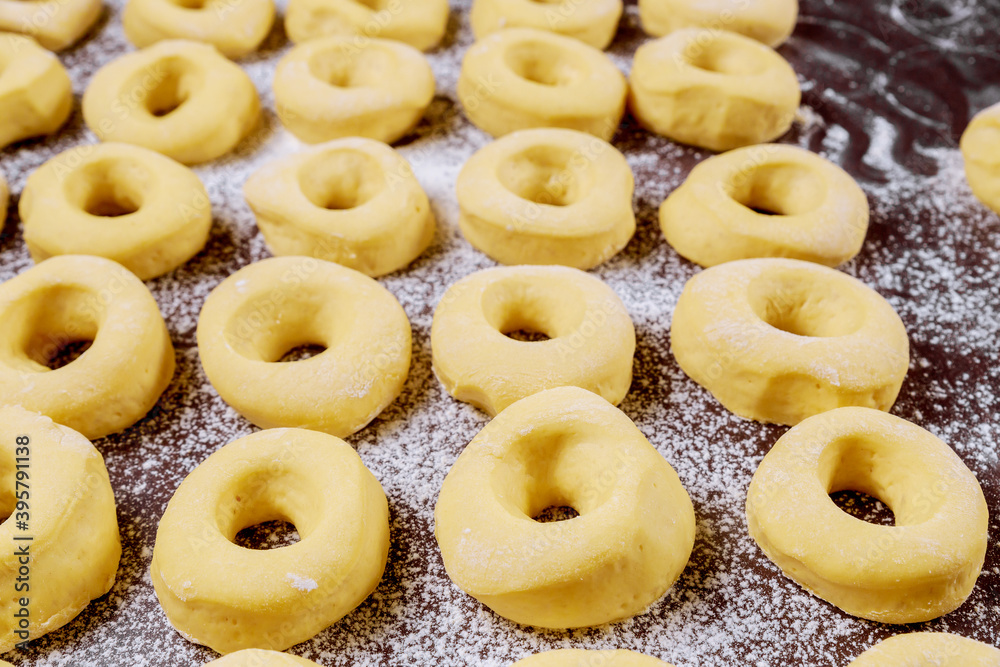 Close up of raw round donuts on table with flour before frying. Close up of raw round donuts on table with flour before frying.