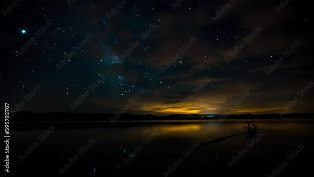 Timelapse or hyperlapse of the stars and the milky way over the lake with reflections