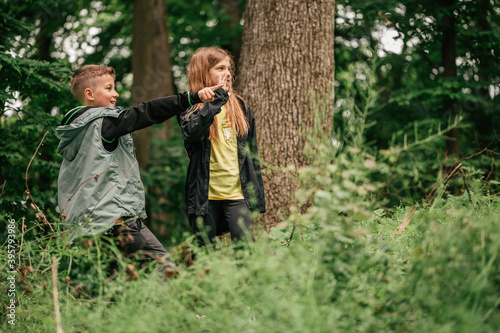 Cute kids waving their arms to someone during forest hike