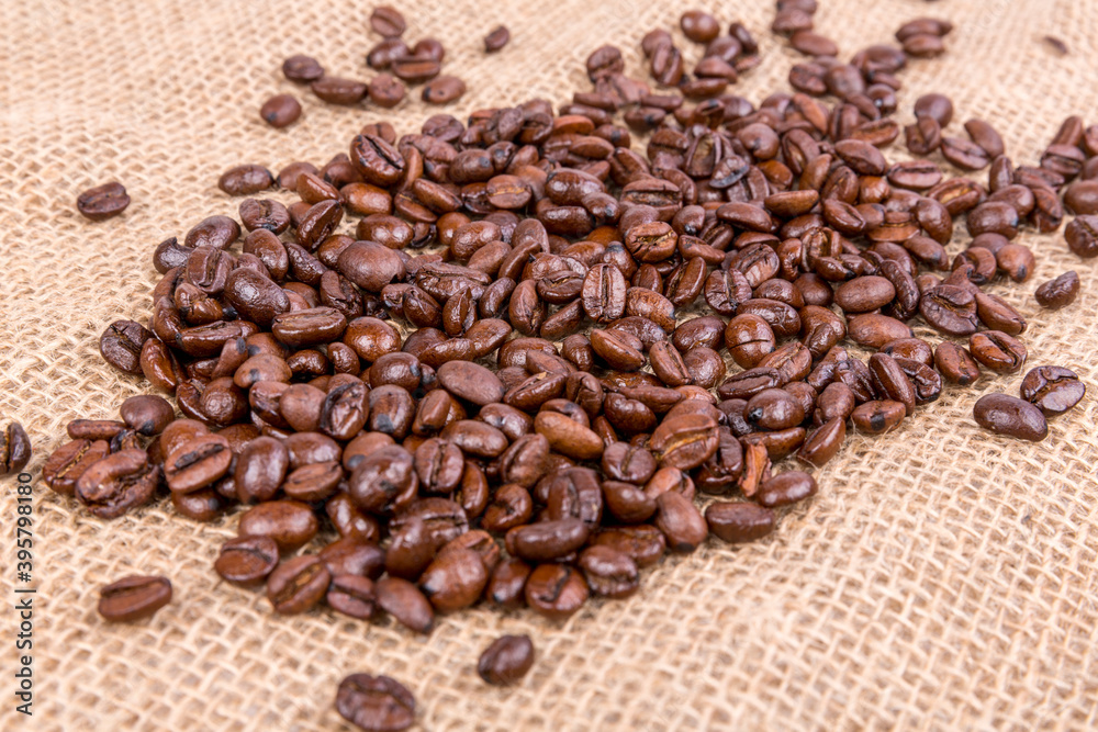 Pounds of roasted brown coffee beans over a burlap textured cloth Pounds of roasted brown coffee beans over a burlap textured cloth