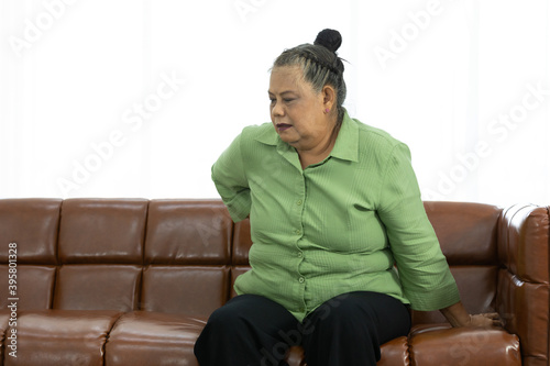 senior asian fat woman suffering from pain in the back and waist on sofa